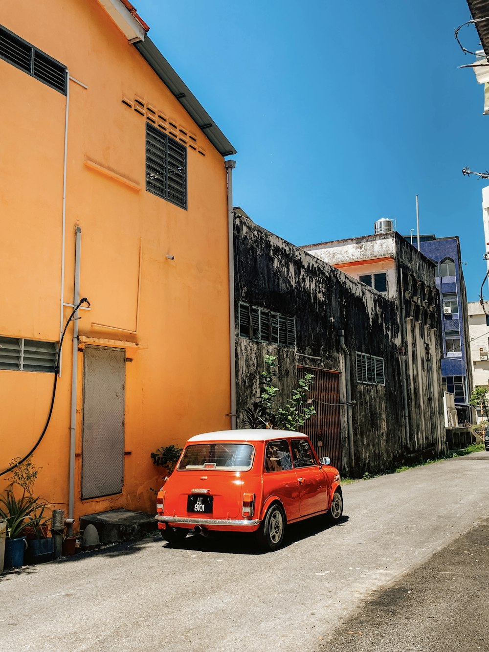 a small red car parked in front of a yellow building