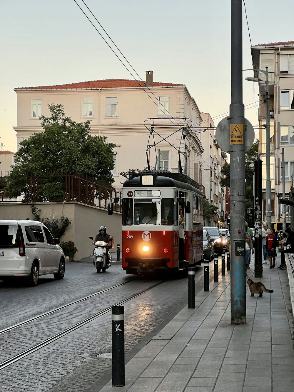 a red and white train traveling down a street next to tall buildings