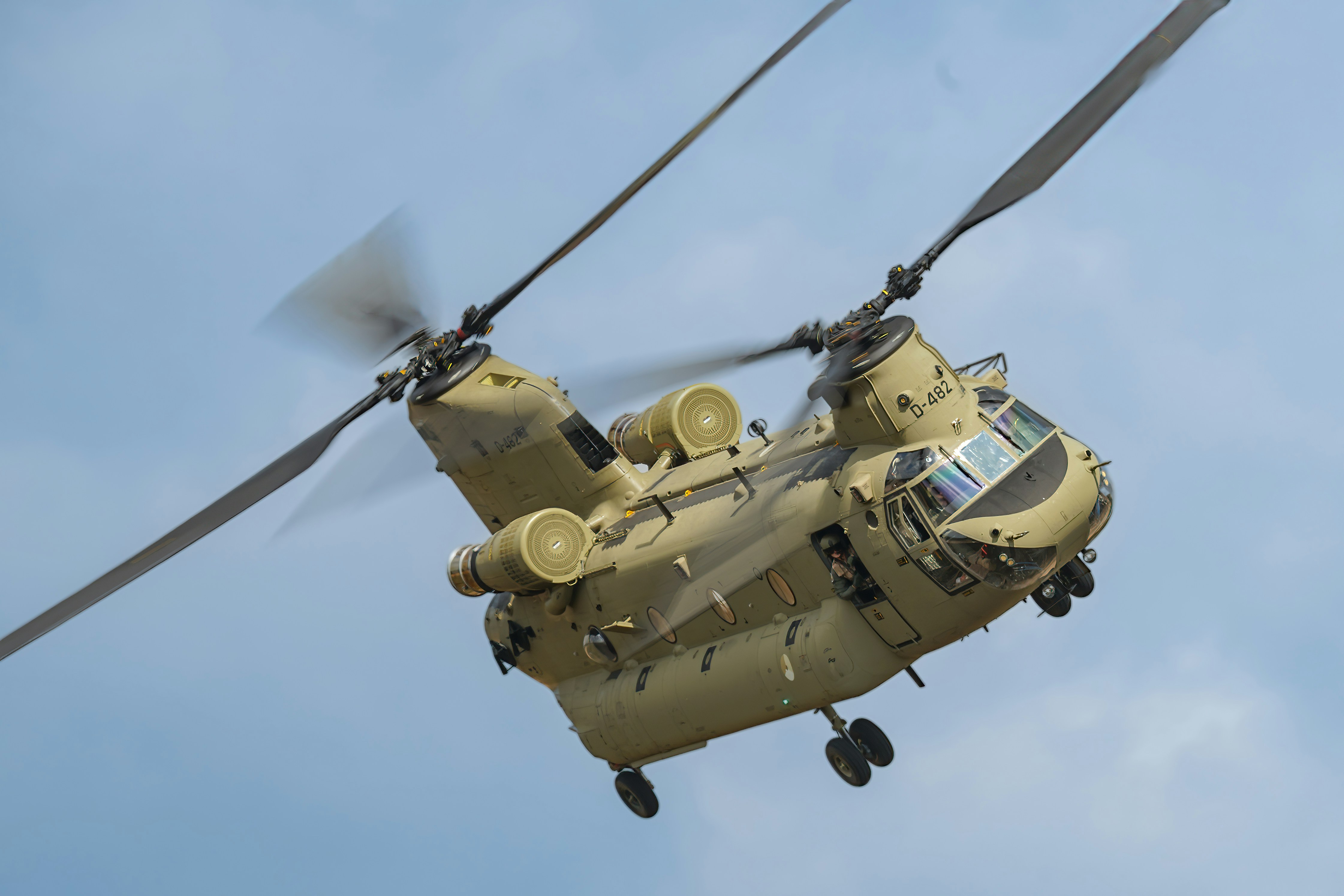 Ein großer Militärhubschrauber fliegt durch einen blauen Himmel