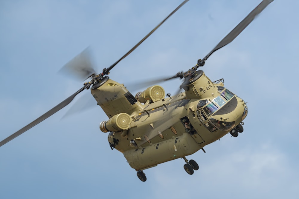 a large military helicopter flying through a blue sky