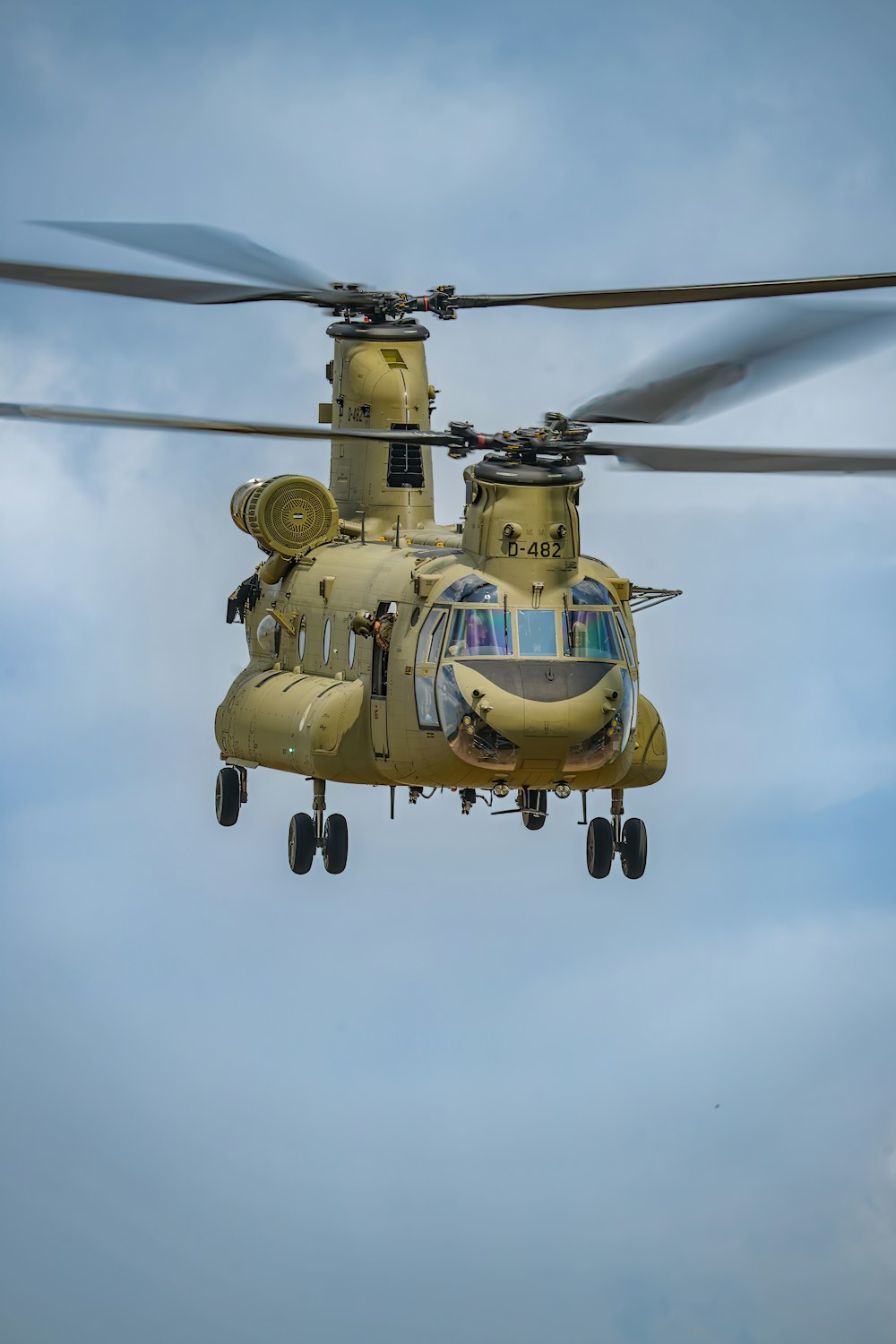 a yellow helicopter flying through a cloudy blue sky