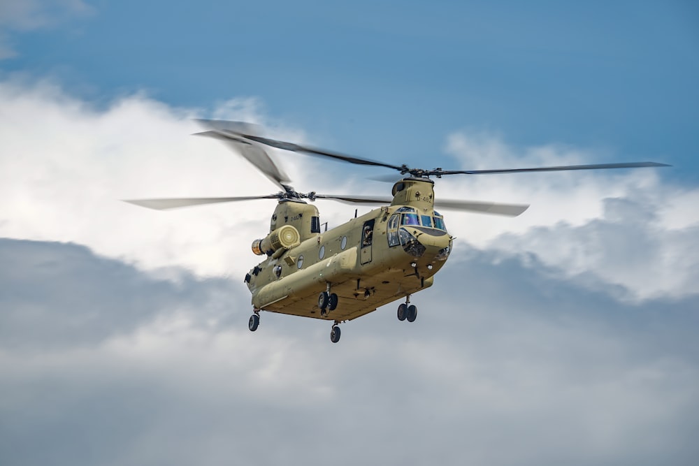 a military helicopter flying through a cloudy sky