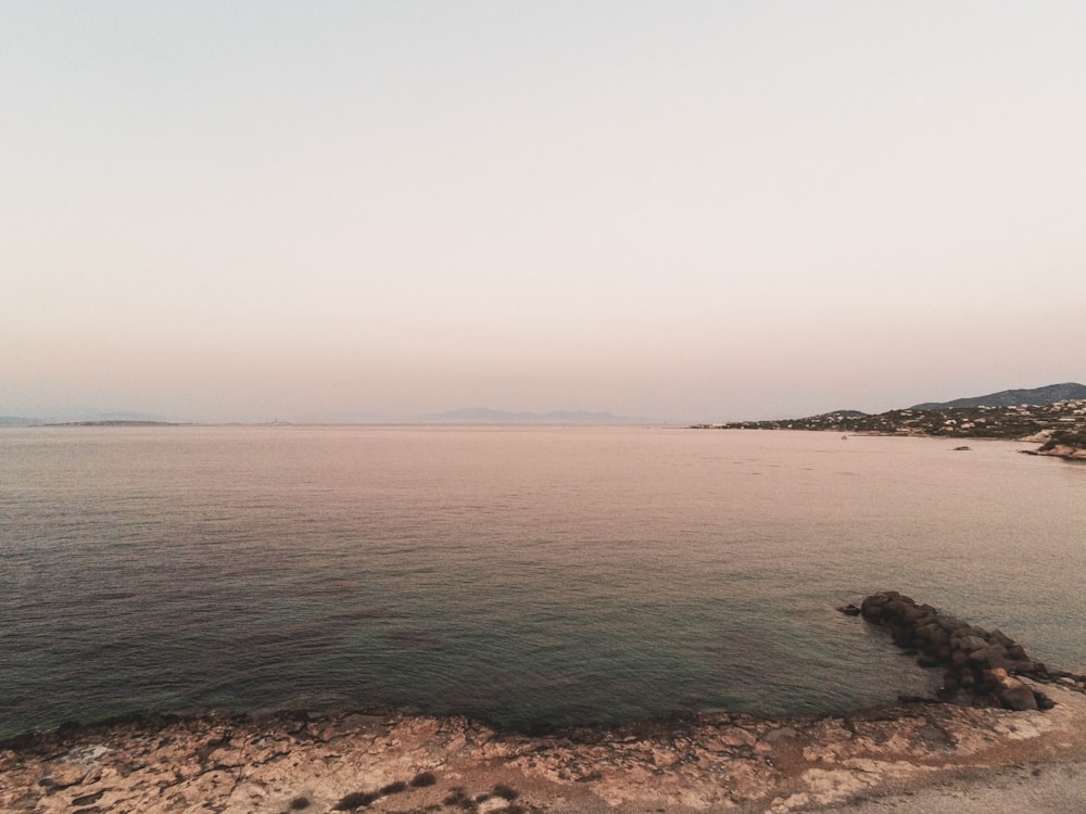 a large body of water sitting next to a rocky shore