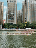 Wide shot of multiple dragon boats racing side by side, vibrant team jerseys contrasting with the deep blue river.