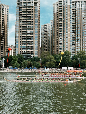 Photo of enthusiastic crowd cheering beside the dragon boat race course under a clear blue sky.