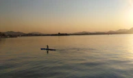 A serene scene of a person meditating by a calm lake during sunset.