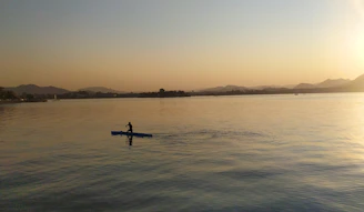 A serene scene of a person meditating by a calm lake during sunset.