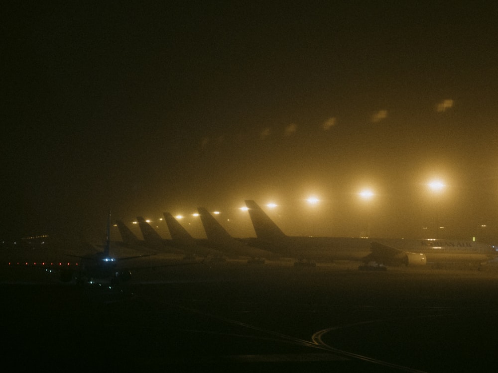 a foggy night at an airport with airplanes on the tarmac
