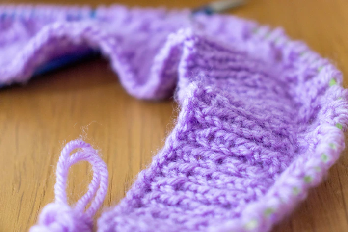 Close-up of a soft purple crochet sweater with intricate stitch pattern.