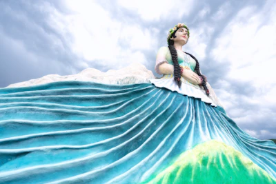 A vibrant depiction of Iemanjá with flowing blue and white robes by the sea.