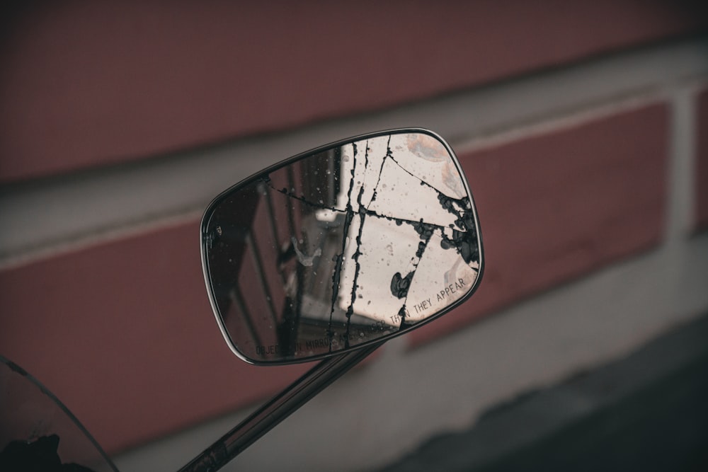 a side view mirror on a motorcycle with a brick building in the background