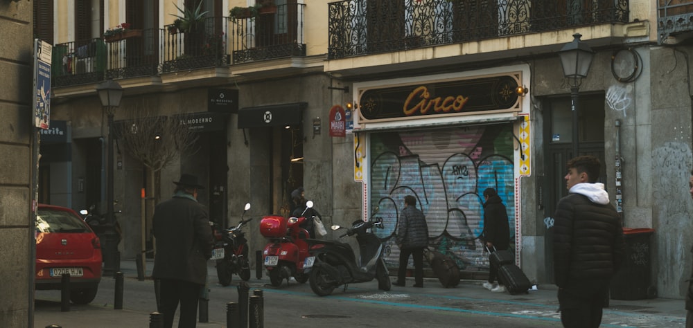 a group of people walking down a street next to parked motorcycles