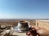 A serene landscape with a cup of coffee in the foreground.