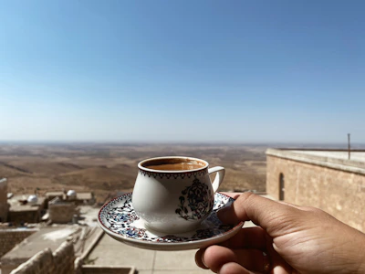 Steaming cup of coffee with a backdrop of traditional Yemeni architecture.