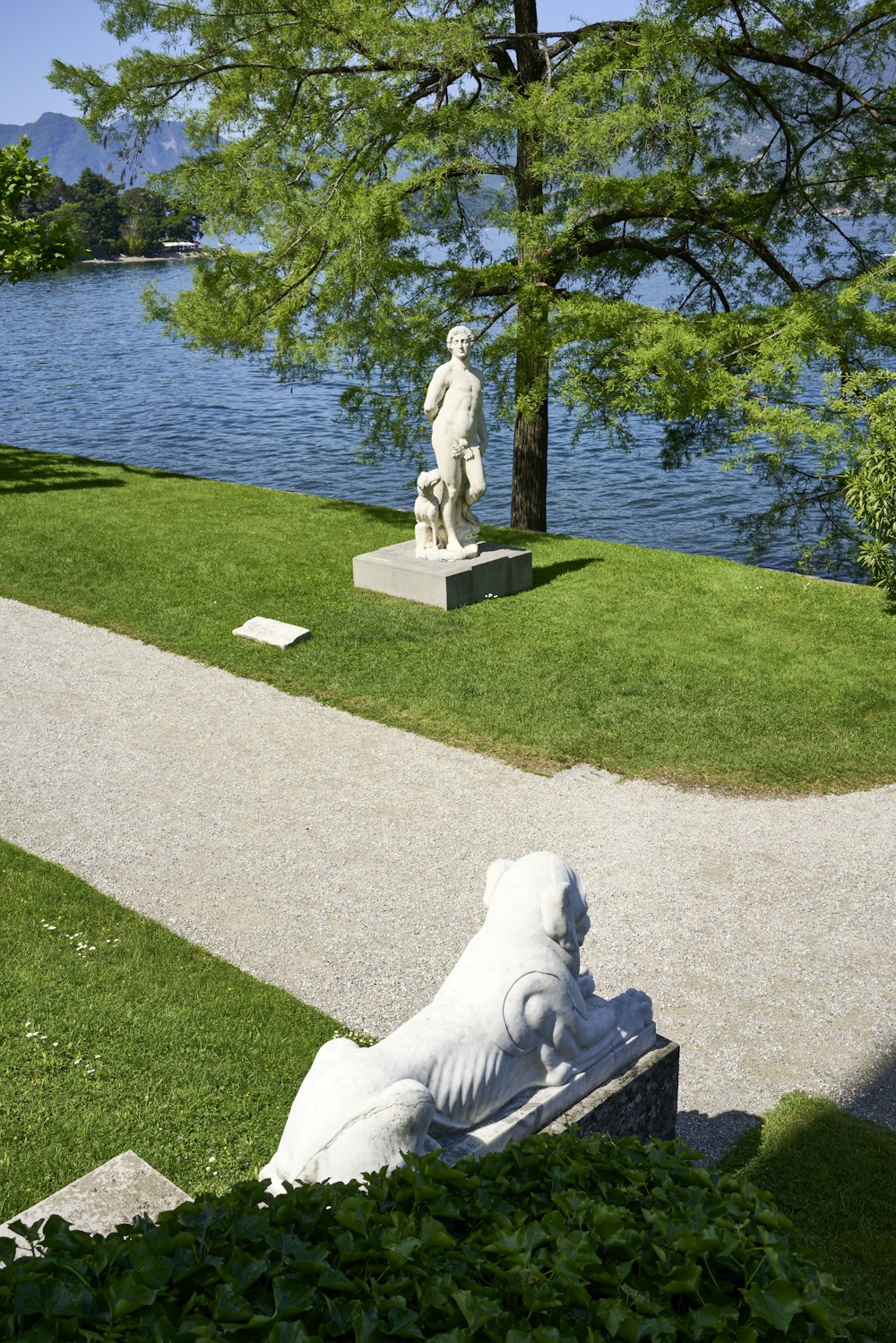 eine Statue einer Frau, die auf einer Bank neben einem Gewässer sitzt