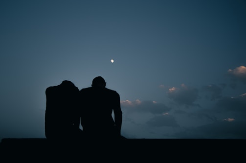 Two lovers sharing a quiet moment beneath a moonlit sky.