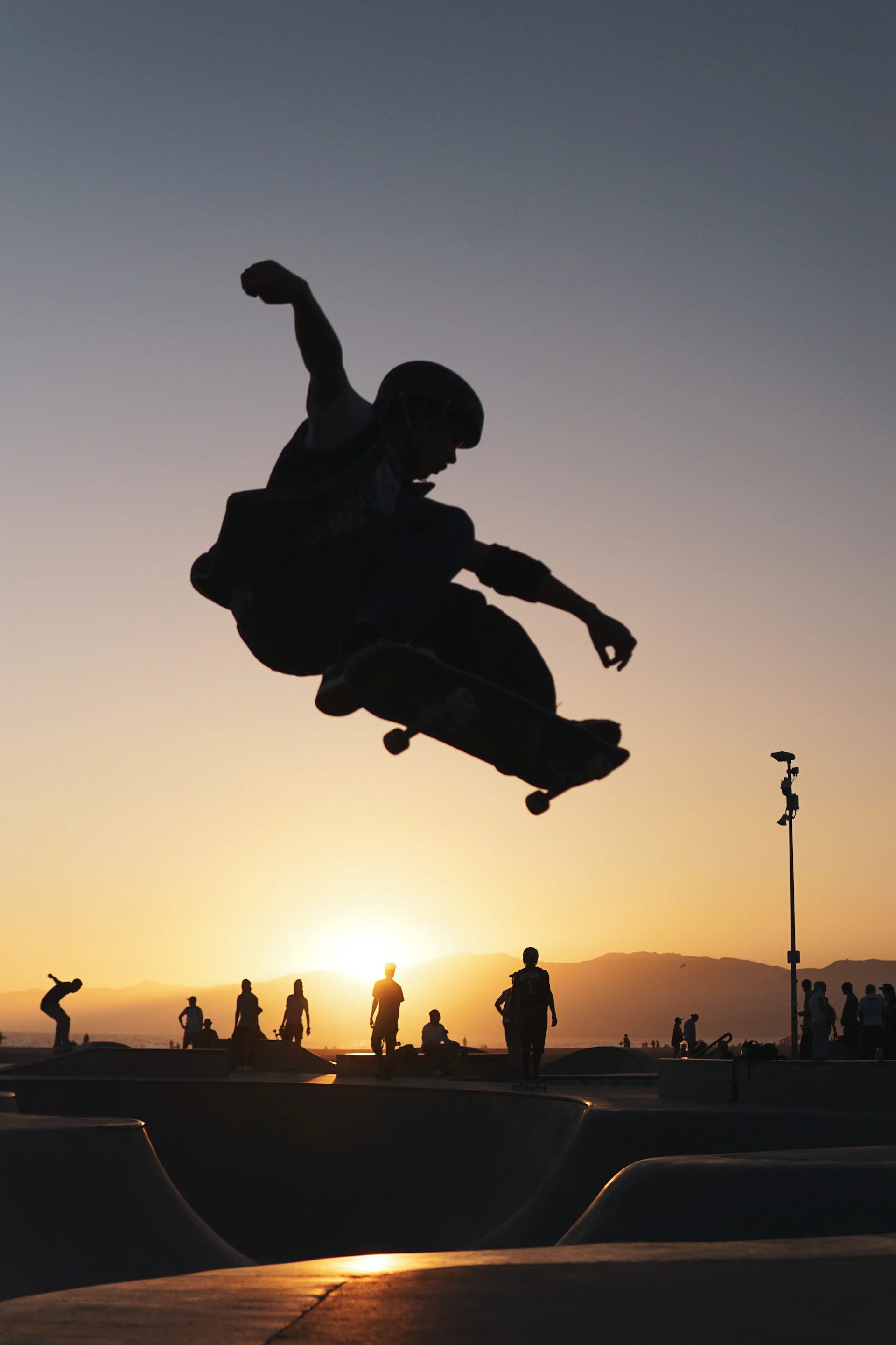 A dynamic shot of a skater mid-air against the vibrant sunset over Baja California's coastline, capturing the raw energy of skate and surf culture.