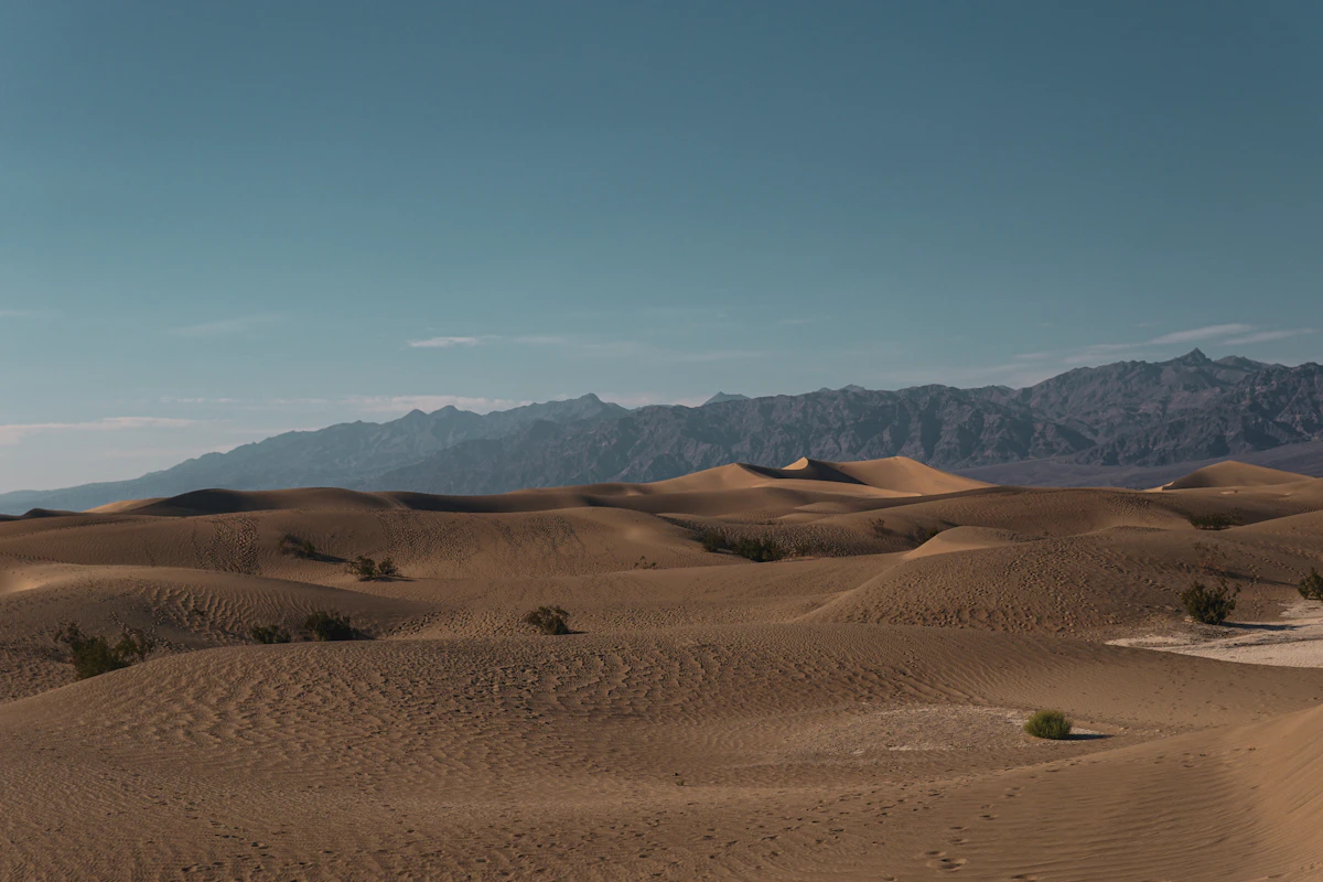 Stark desert landscape with distant ridgelines under a hot, hazy sky — illustrative imagery of the arid Mojave/Death Valley type terrain across which the National Weather Service's May 10-12, 2026 extreme-heat warnings have been issued, with Death Valley forecast to hit 111°F on Monday.