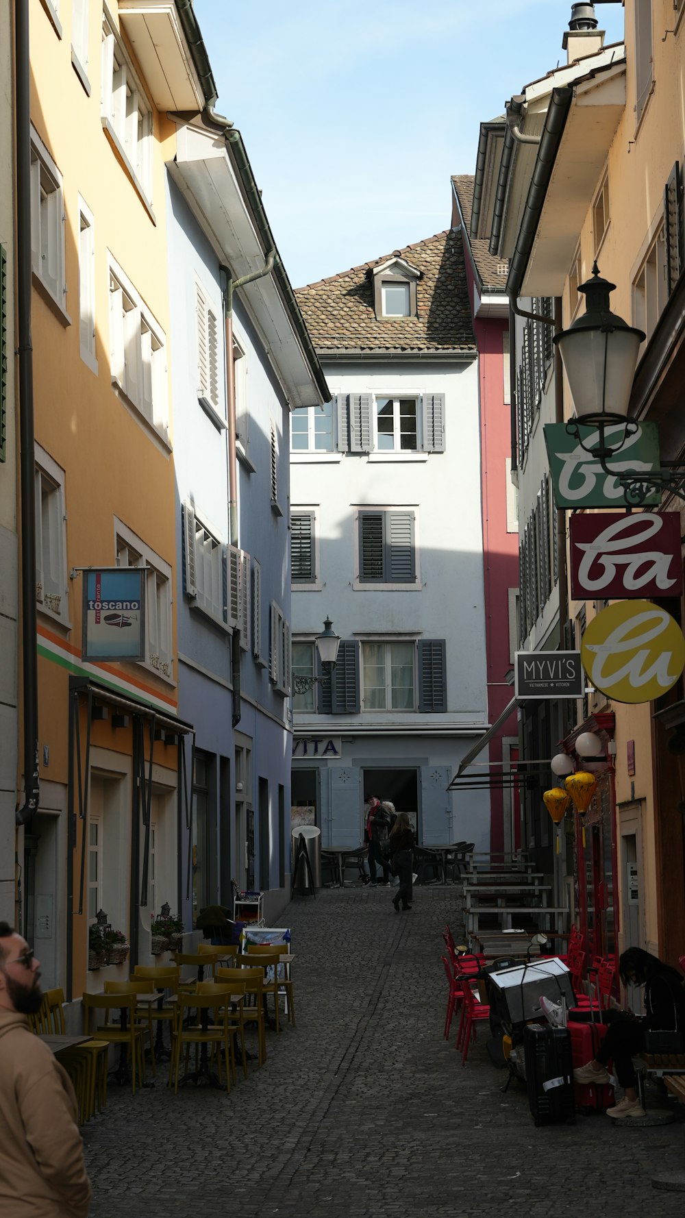 a narrow alley way with tables and chairs