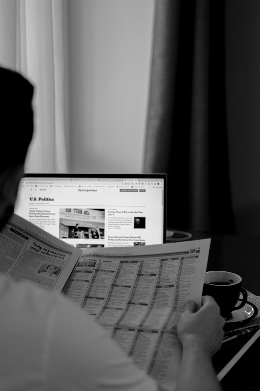 a man sitting at a desk reading a newspaper