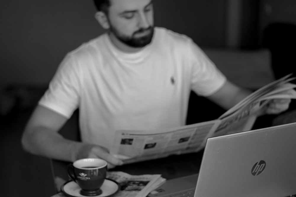 um homem sentado à mesa lendo um jornal