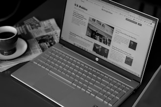 a laptop computer sitting on top of a desk next to a cup of coffee