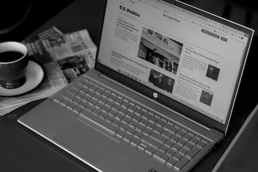 a laptop computer sitting on top of a desk next to a cup of coffee