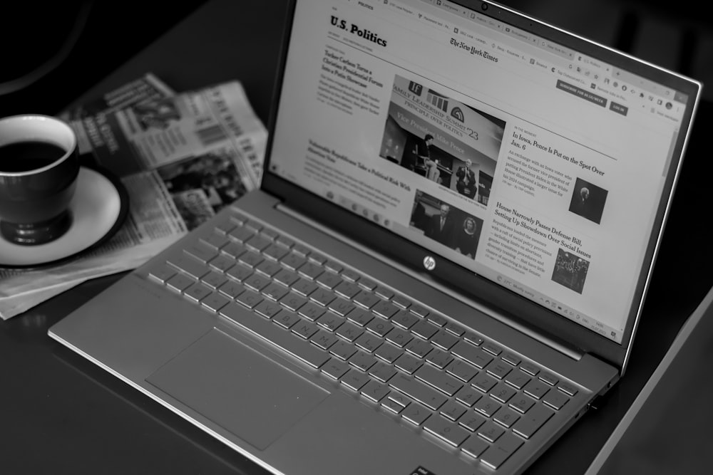 a laptop computer sitting on top of a desk next to a cup of coffee