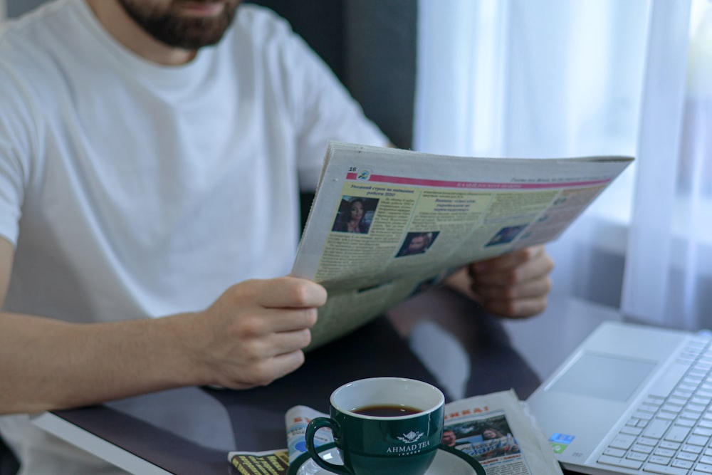 a man sitting at a table reading a newspaper