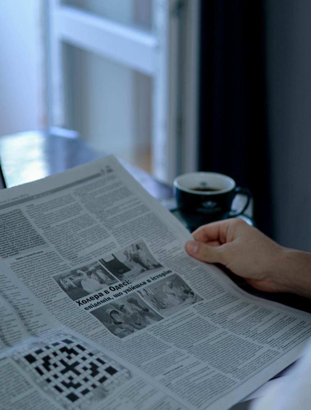 a person reading a newspaper with a cup of coffee