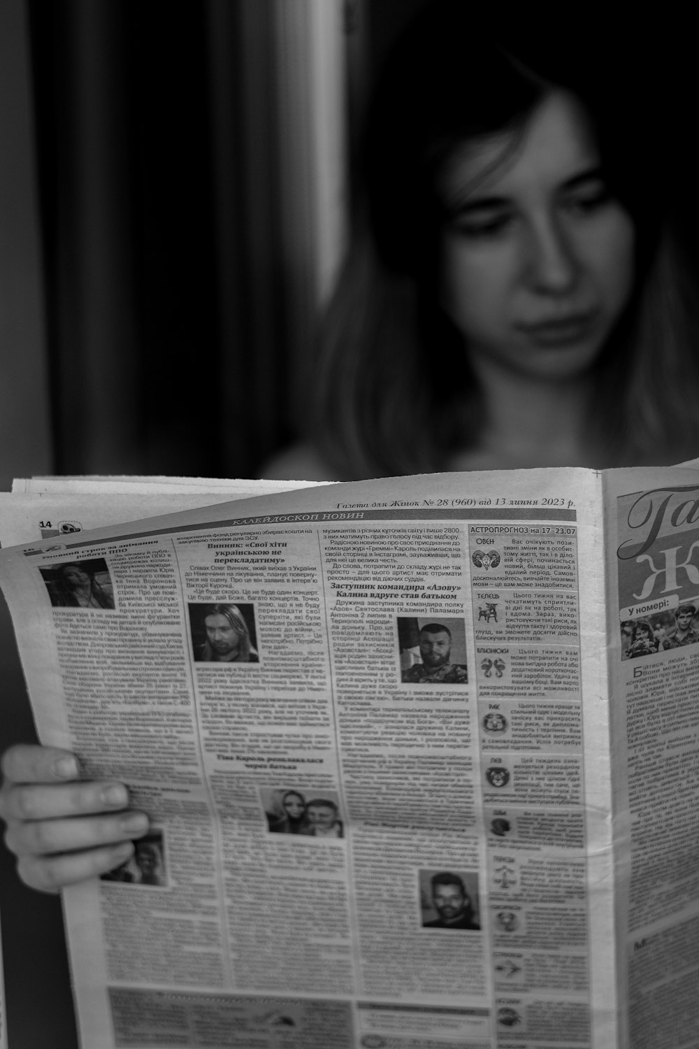 a woman reading a newspaper while sitting in a chair