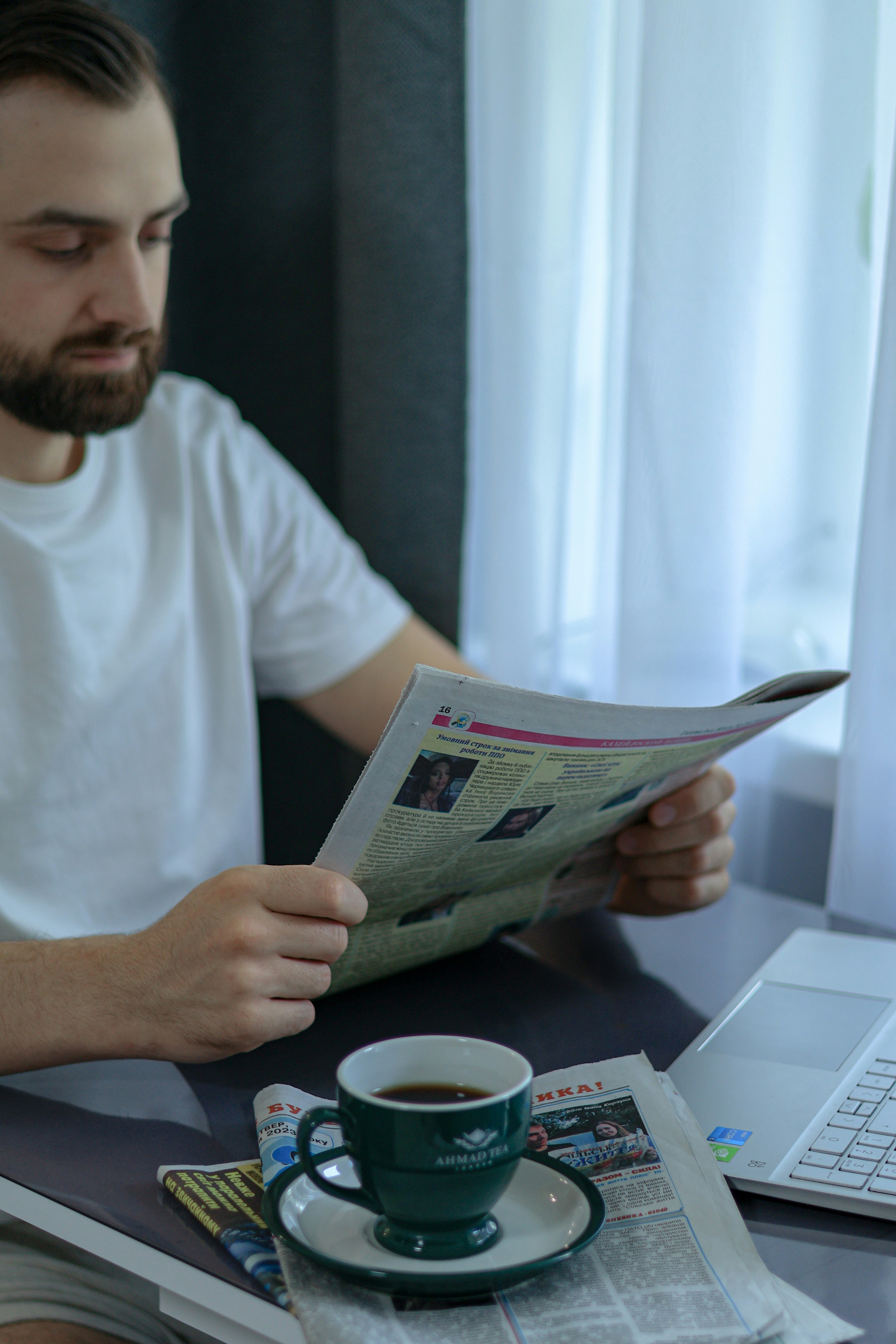 Morning coffee cup next to a newspaper with business headlines, warm kitchen light, relaxed reading setting