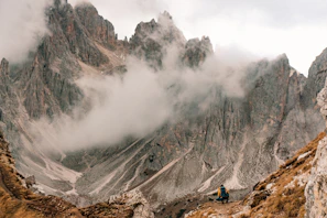 A hiker pausing on a rocky trail overlooking the misty peaks of the Rhodope Mountains at sunrise.
