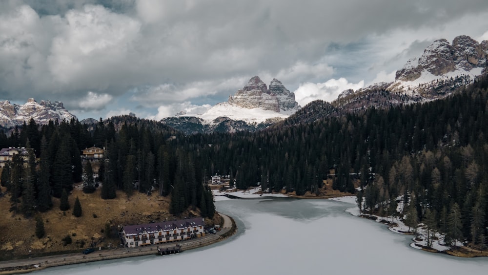 a lake surrounded by trees and mountains under a cloudy sky