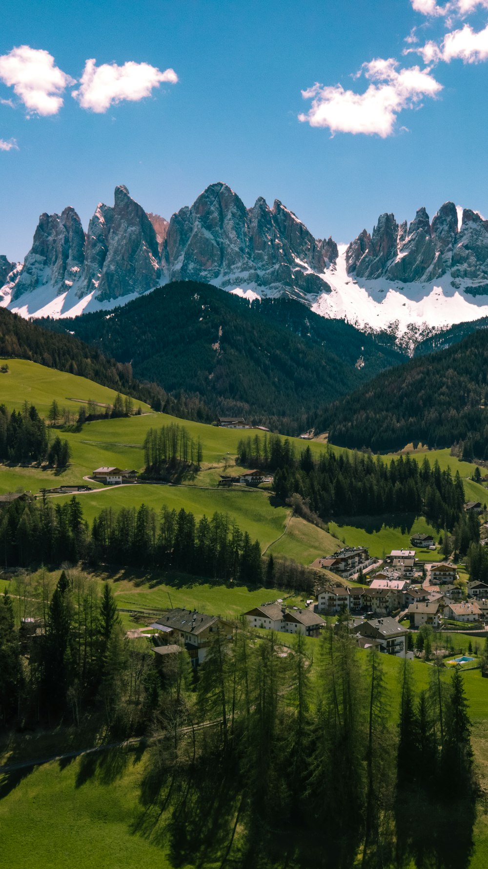 a scenic view of a mountain town with snow capped mountains in the background