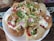 A plate of Indian street food, specifically pani puri or golgappa, filled with vibrant ingredients. The round, crispy puris are topped with a mix of yogurt, tamarind chutney, finely chopped onions, fresh coriander, and crispy sev. Bright colors and a variety of textures are prominent.
