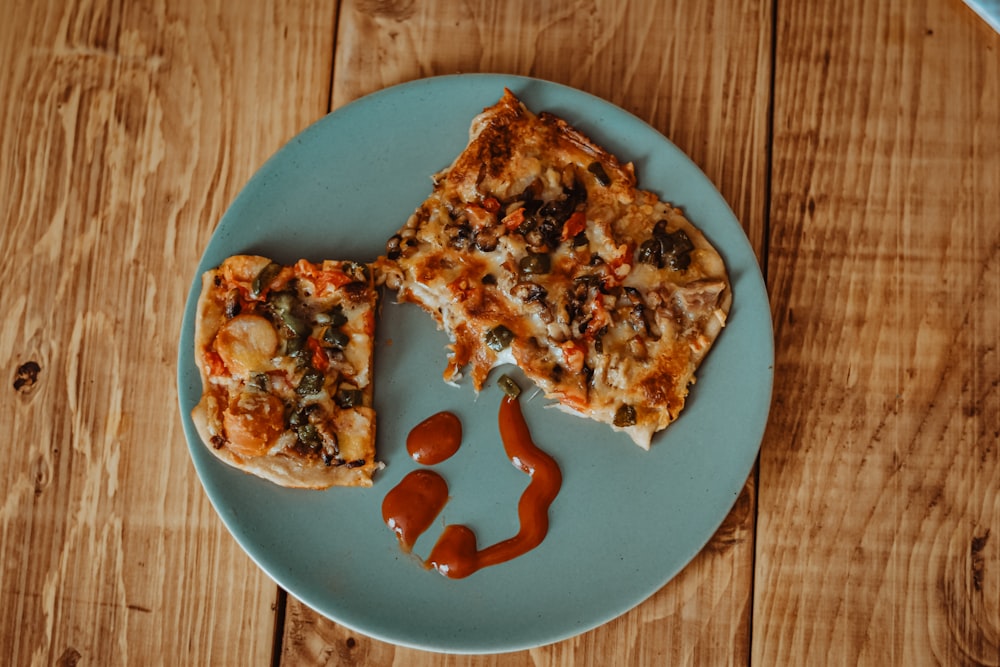 two pieces of pizza on a plate with ketchup