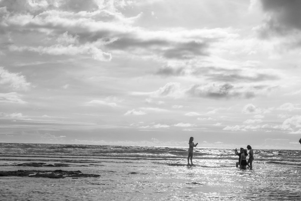 a group of people standing on top of a beach next to the ocean