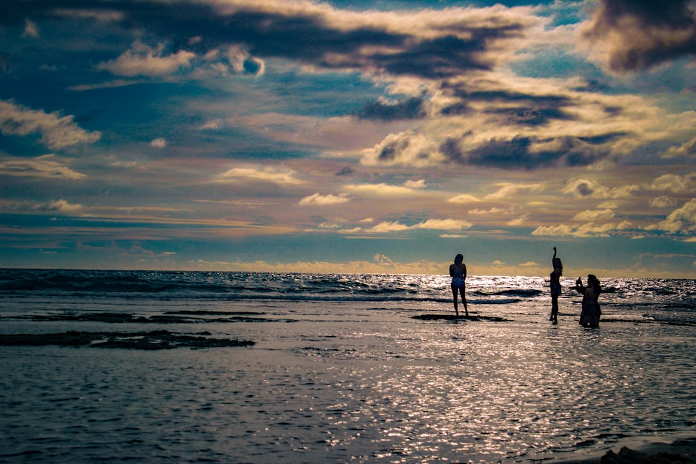 a couple of people standing on top of a beach next to the ocean