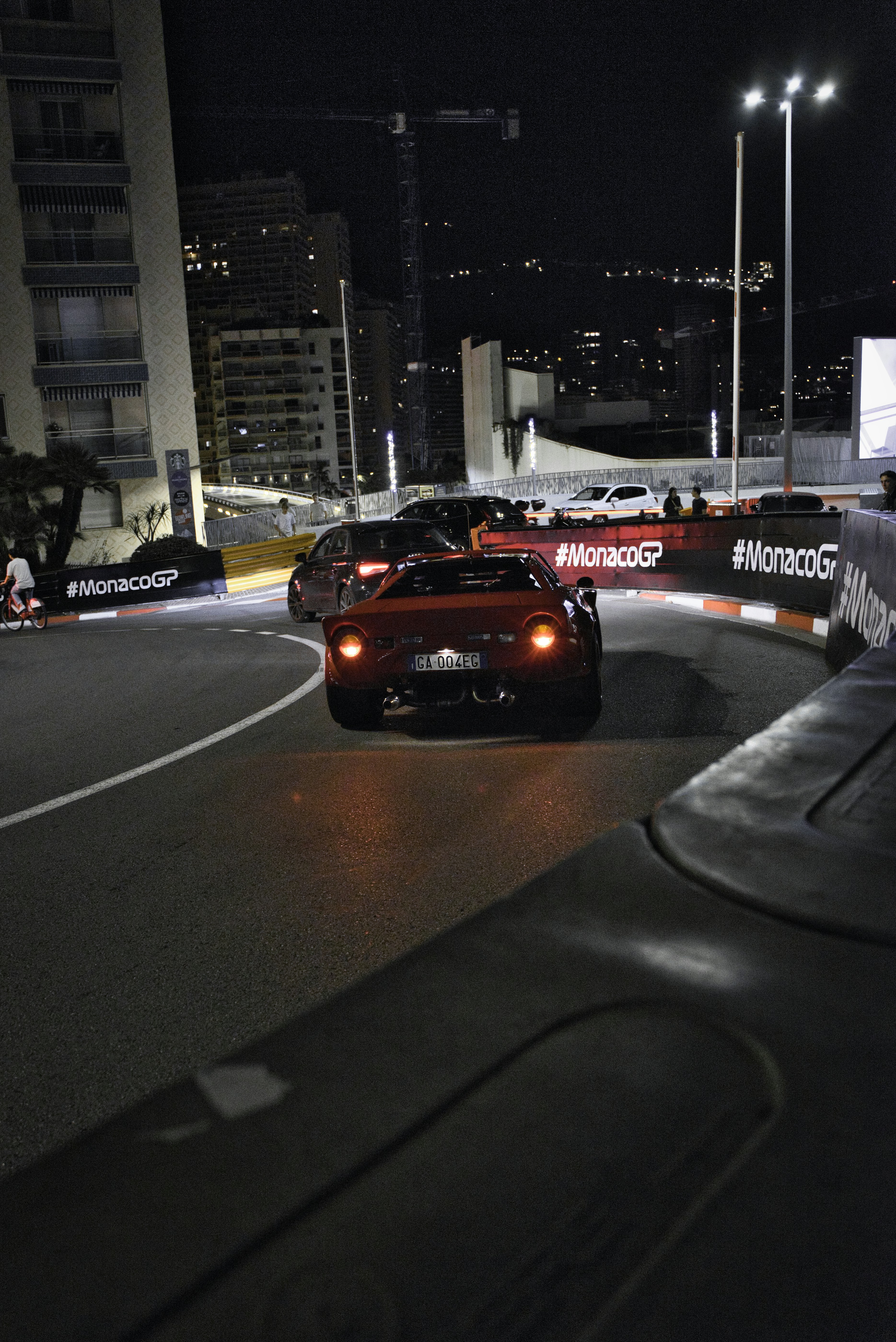 a couple of cars driving down a street at night