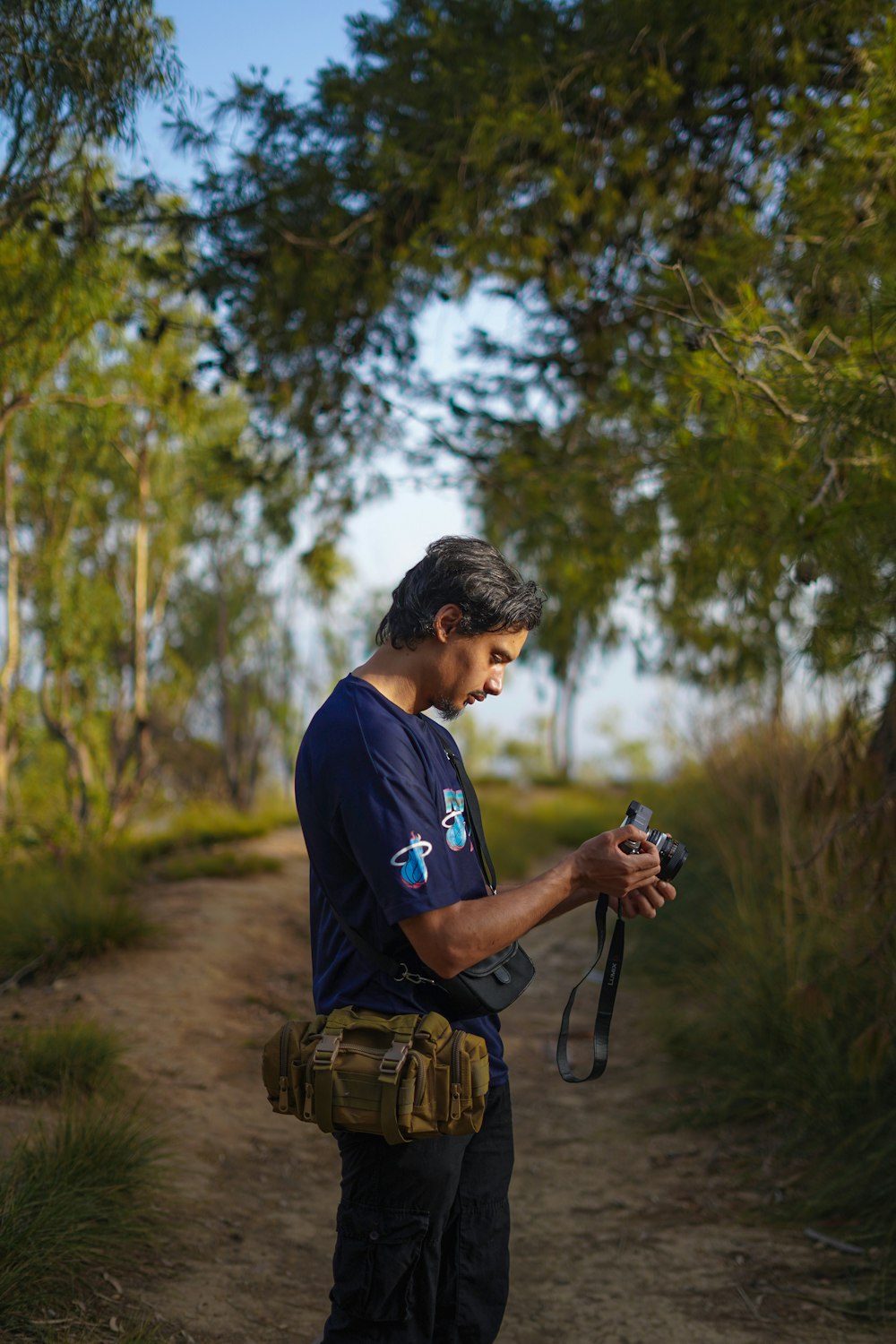 a man standing on a dirt road holding a camera