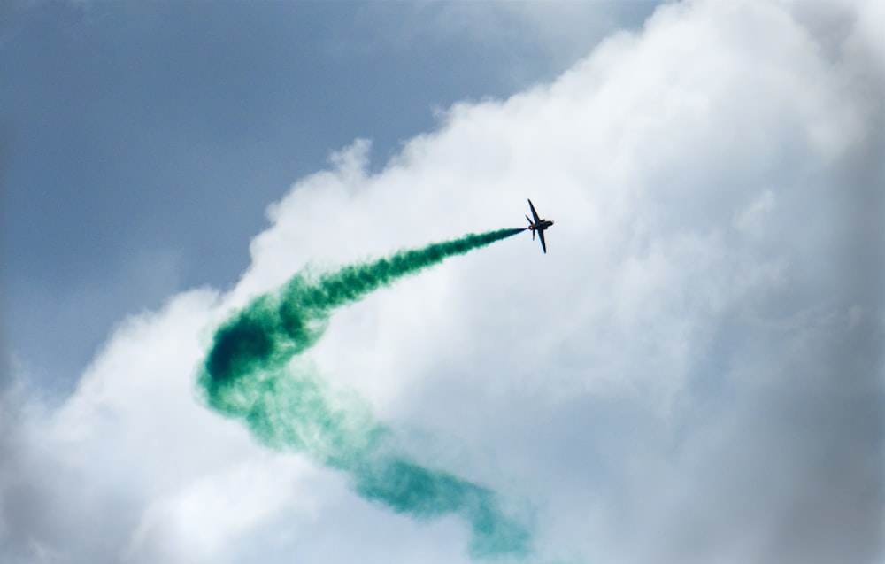 Un aereo che vola nel cielo lasciando una scia di fumo verde