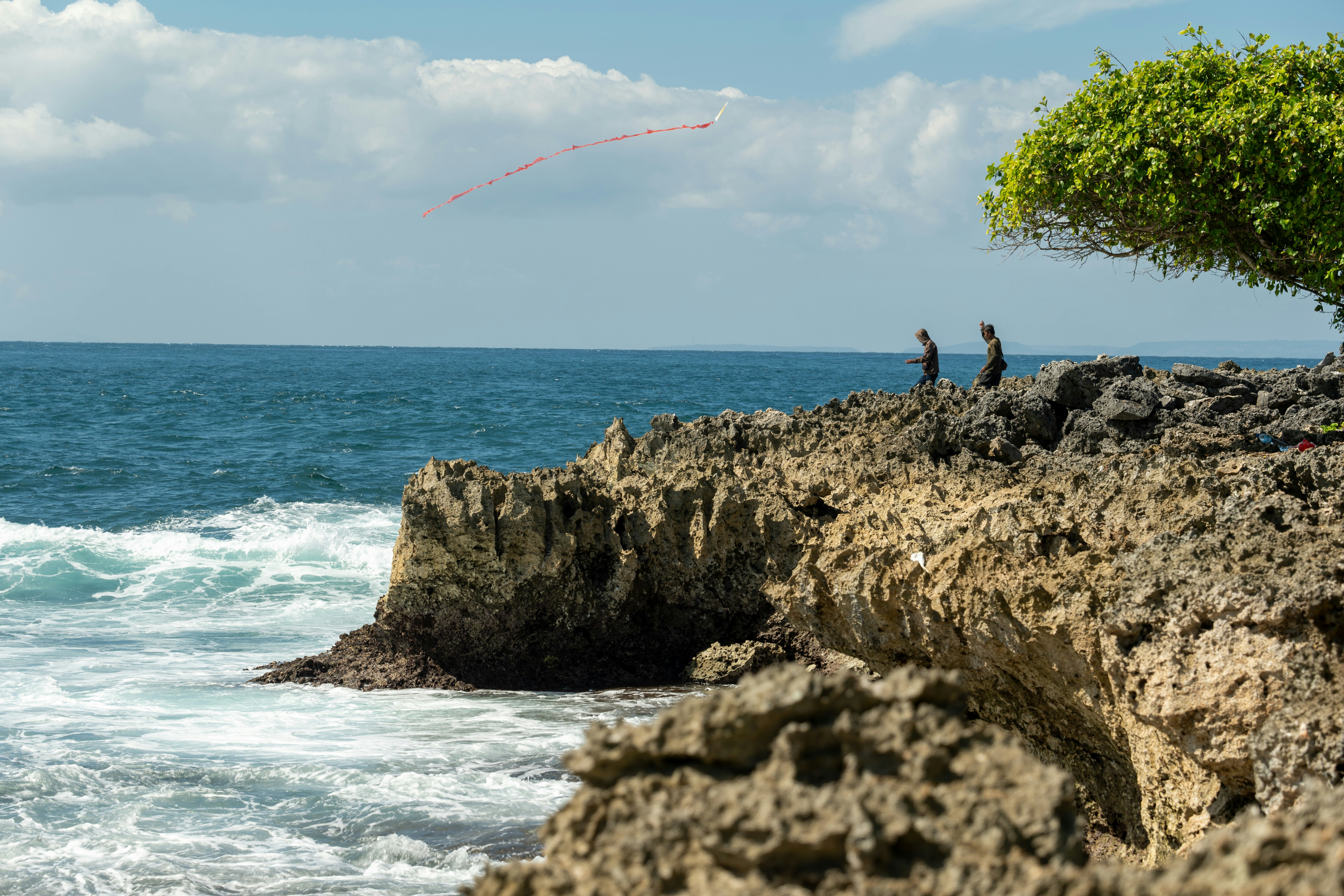 a couple of people standing on top of a rocky beach