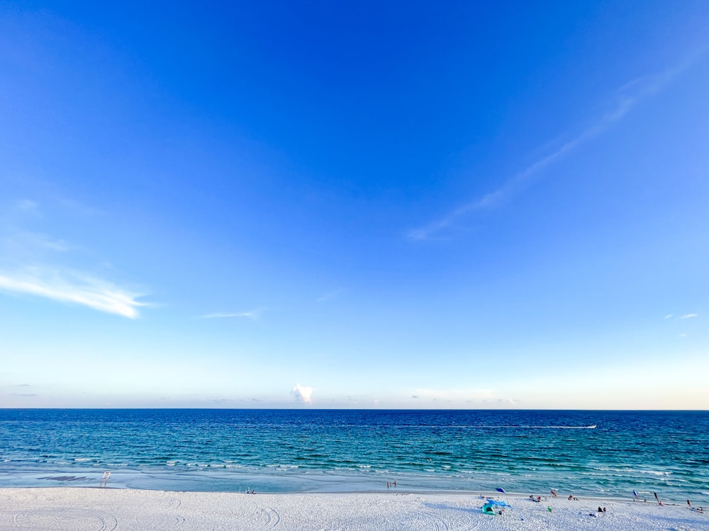 a sandy beach with a blue sky and ocean in the background