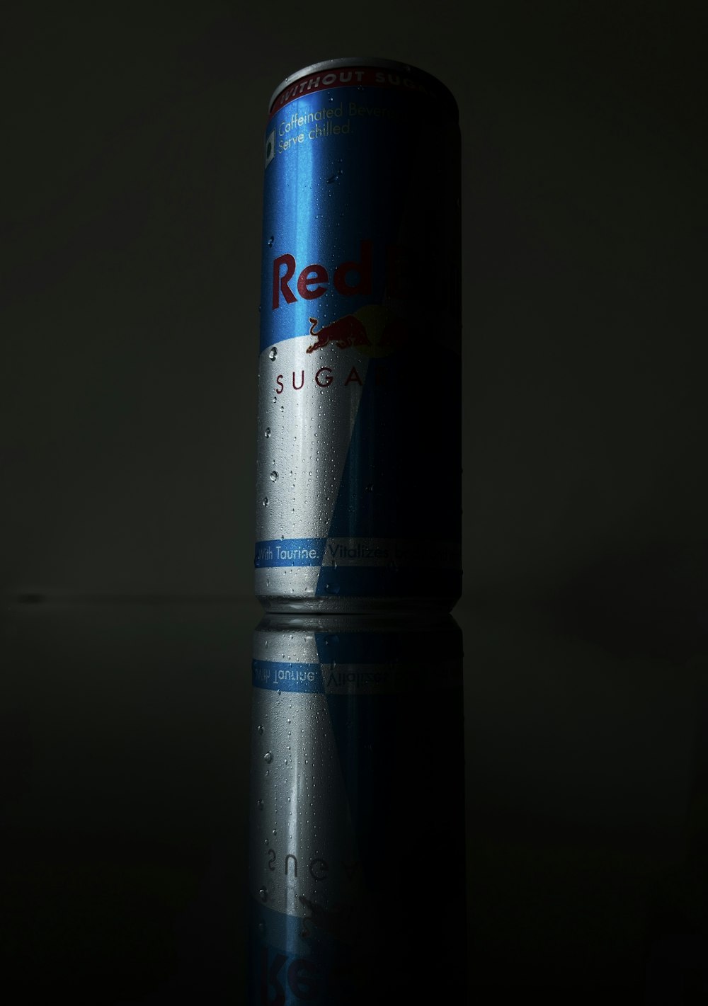 a can of red bull on a reflective surface