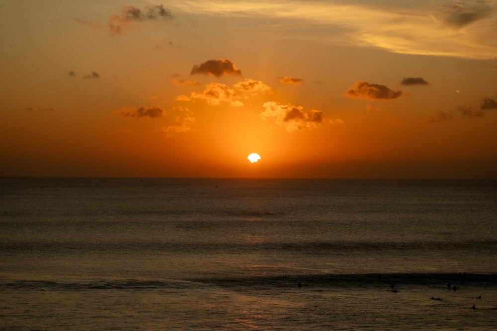 the sun is setting over the ocean on a cloudy day