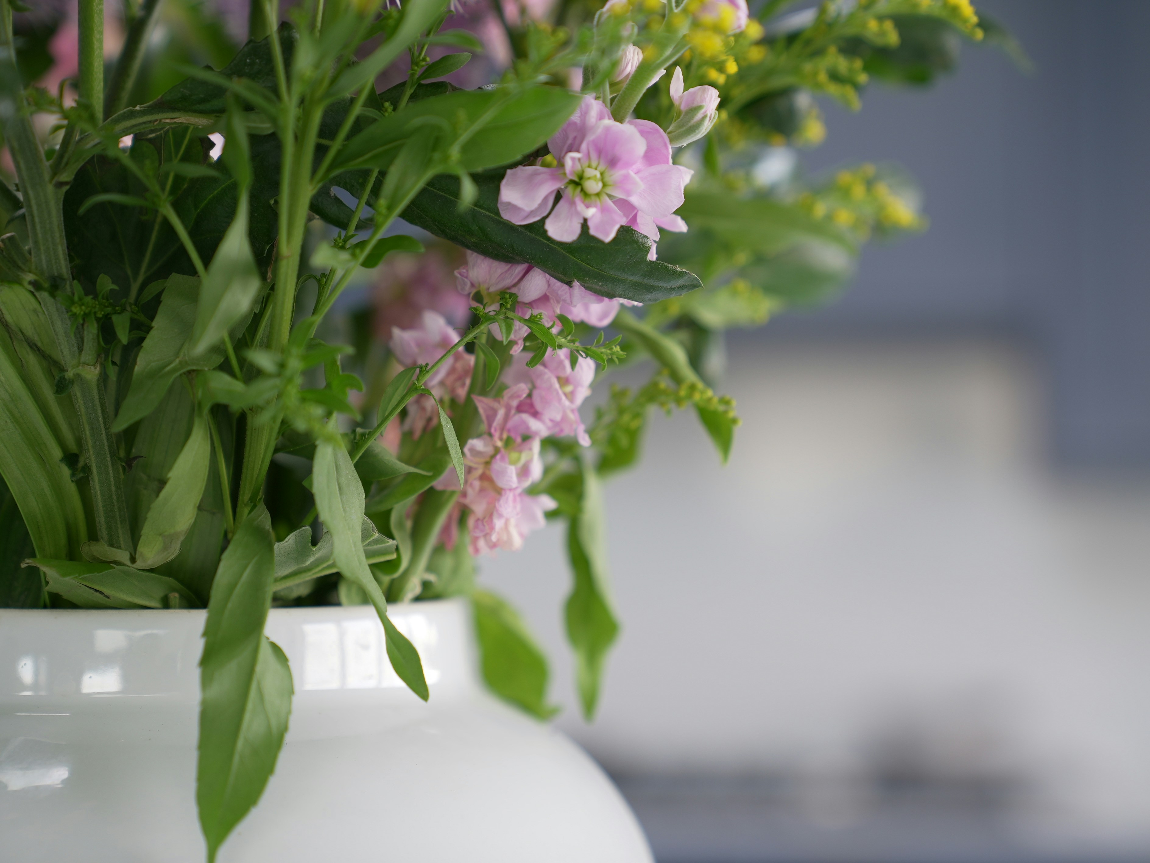 a white vase filled with pink and yellow flowers