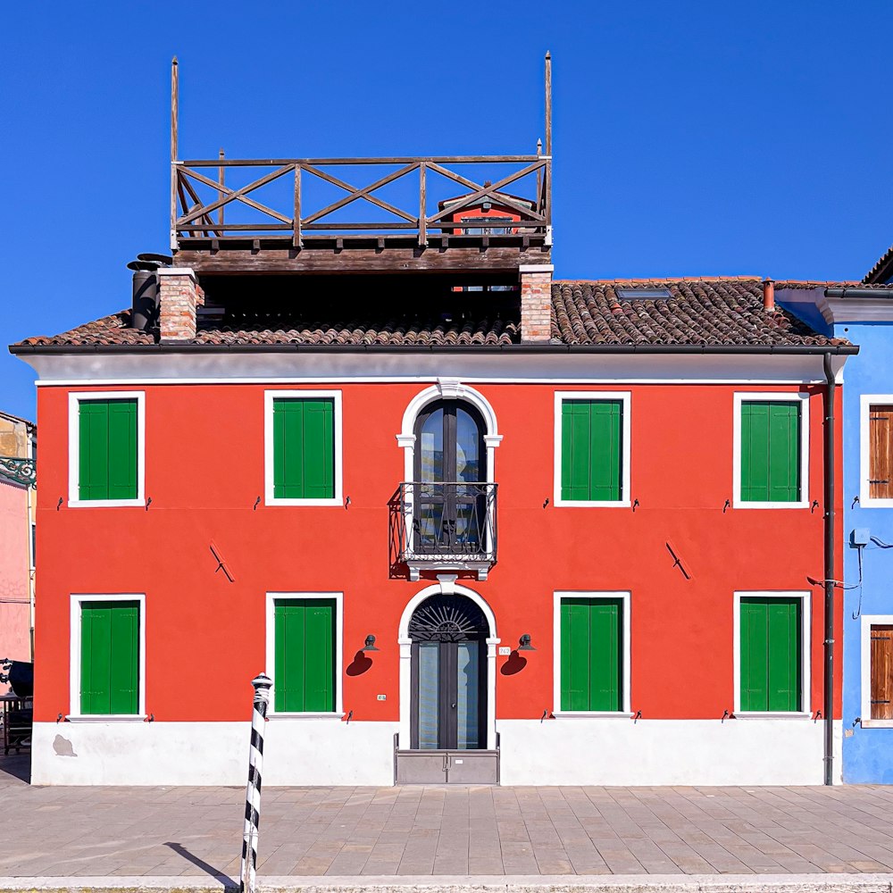 a red building with green shutters and a balcony