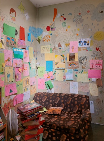 A cozy therapy space with colorful cushions and children's drawings.
