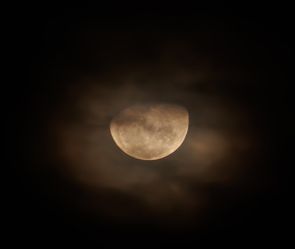 the moon is seen through the clouds in the dark sky